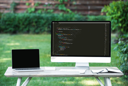 用空白屏幕和电脑在户外餐桌配有编程语言代码的笔记本图片