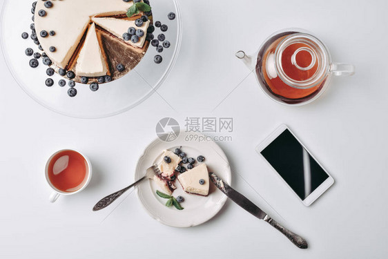 桌上有蓝莓和茶的芝士蛋糕片的顶部视图图片