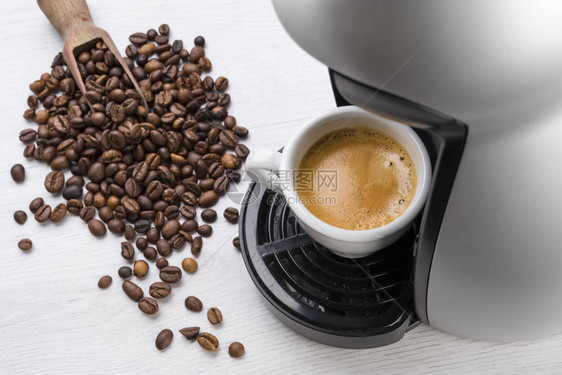 咖啡杯刚装满的咖啡机上图片