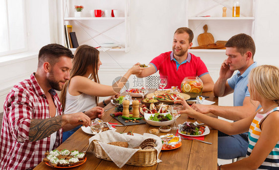 朋友聚会一群快乐的人在咖啡馆餐厅的派对餐桌上聊天吃饭传递健康的饭菜年轻的公司在室内的木桌上用酒图片