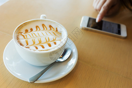 咖啡厅用手机在木桌棍上喝热图片