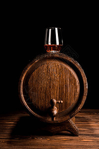 黑色背景下木桶上的一杯威士忌图片