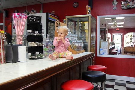 一个十月大的女婴坐在销售柜台在旧时尚的冰淇淋图片