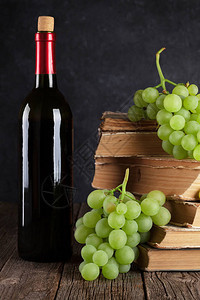 红葡萄酒瓶白葡萄和桌上的书图片