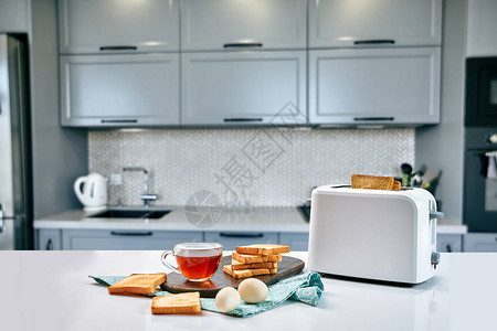 在舒适的厨房享用早餐有用和美味的食物在阳光充足的地方享用早餐烤面包机中的茶和图片
