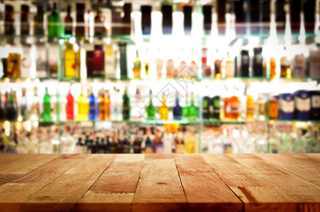 在模糊五颜六色的酒精饮料瓶背景的木酒吧上面背景图片