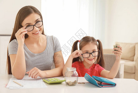 快乐的小女孩和母亲坐在室内桌前她妈坐图片