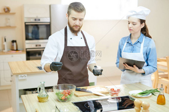 两位在餐厅厨房工作的年轻专业厨师的画像图片