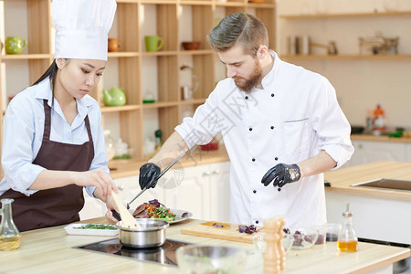 两名专业厨师在现代餐厅厨房工作时烹饪美味菜盘的肖像图片