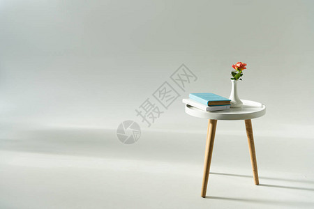 现代咖啡桌上灰色背景的花瓶朵和书图片