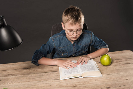 身戴眼镜的中学生男孩在桌边用灯和梨子灰图片