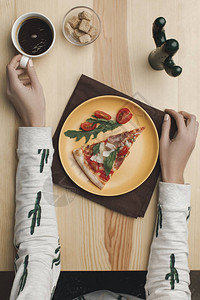 妇女坐在桌边盘子上披萨片和咖啡杯图片