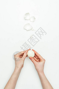 女人剥熟鸡蛋的裁剪图像在白色上分离图片