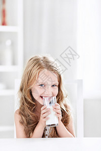 美丽的小女孩在厨房里喝牛奶在图片