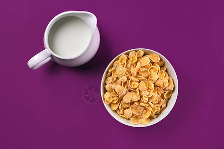 有玉米片的碗紫色背景的一壶牛奶最顶端视野复制空间静图片