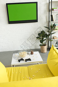 在客厅黄色沙发附近的桌边有爆米花和摇摆棍的玻图片
