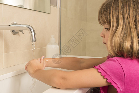 孩子在水龙头下洗手的特写图片