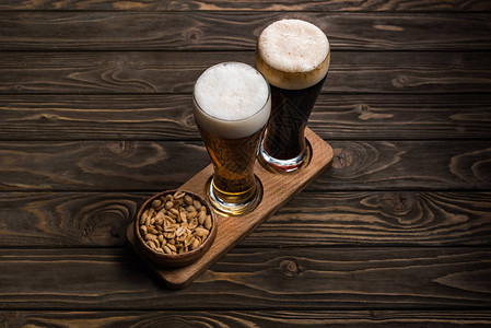 碗旁的黑啤酒杯和轻啤酒杯木图片