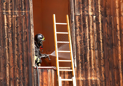 无所畏惧的消防员与水合剂提供大量用水当在一栋房屋图片
