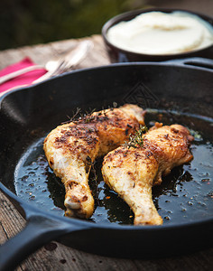 铸铁平底锅中的两条烤鸡腿图片