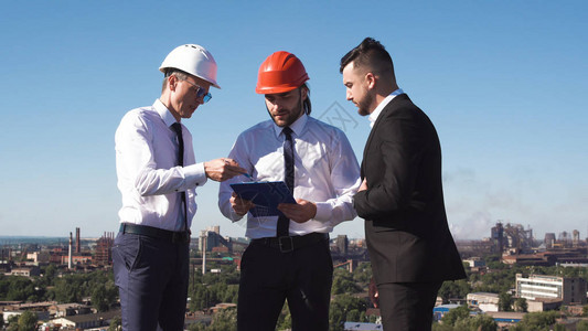 一群男商人和建筑师或工程师站在屋顶上与图片
