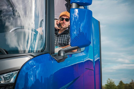 卡车司机从他的半卡车里面打电话交通运输业30多岁的背景图片