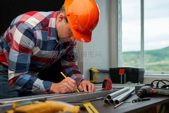 一个穿格子衬衣的工程师在铝剖面图上标注大小有选择地聚图片