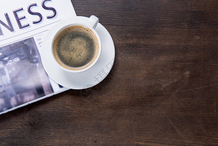 木桌上咖啡杯和报纸的特写俯视图背景图片