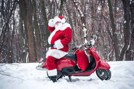 圣诞老人坐在红色摩托车上在冬季公园调图片