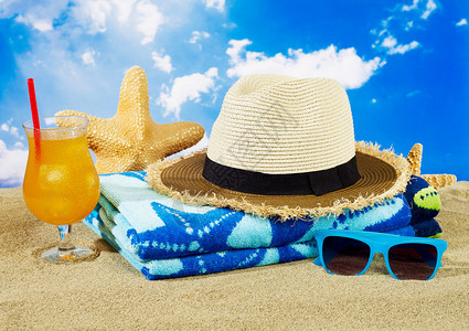 毛巾帽子鸡尾酒和太阳镜在沙子上图片