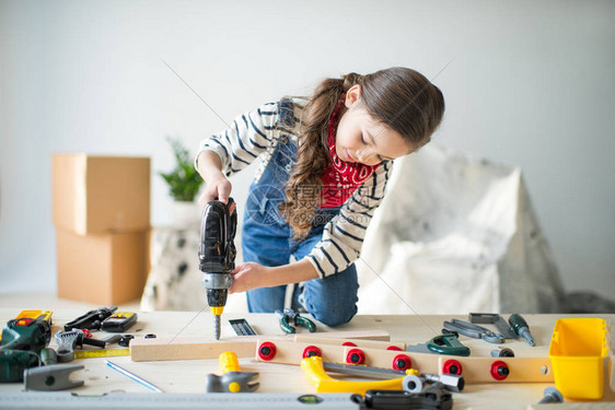 美丽的小女孩用玩具工在桌子图片