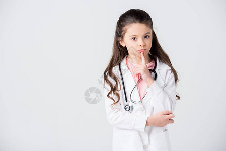穿着医生服装的漂亮小女孩握着手指在下巴上看着被白色图片