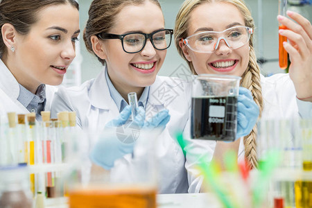 年轻笑着微笑的女科学家在化学实验背景图片