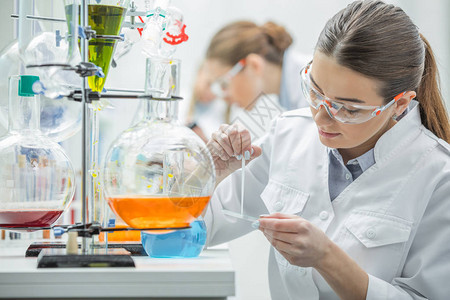 从事实验室化学样本工作的年轻女科学家的背景图片