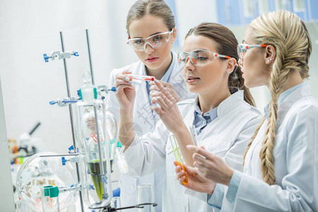 三名年轻集中的女科学家在化学实验室中进行实验图片