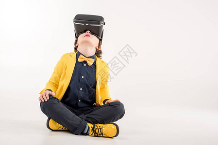 虚拟现实耳机的孩子坐在灰色背景图片