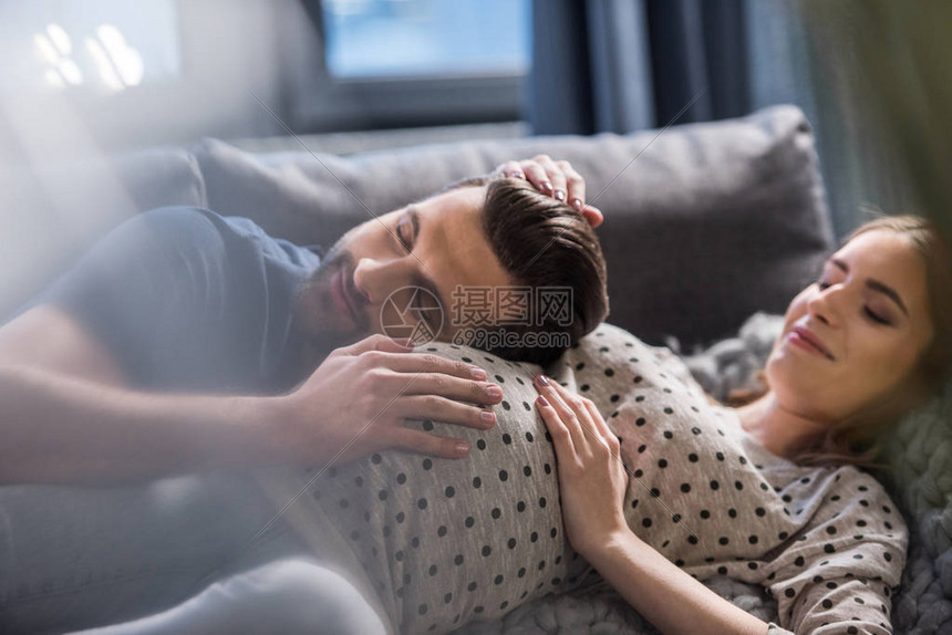 快乐的男人听着笑的孕妇躺在图片