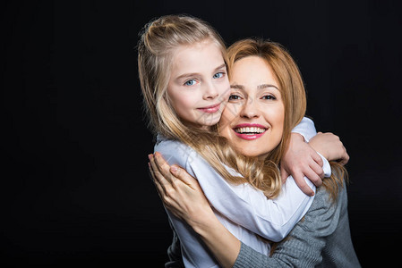 年轻母亲和她可爱的女儿拥抱和笑着微笑在镜头中被图片