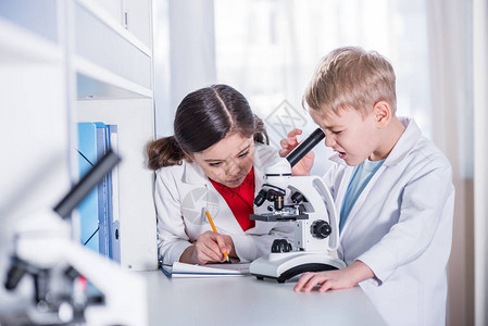 使用显微镜的小男孩和在化学实验室图片