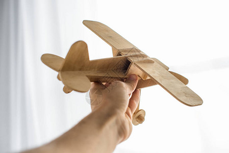 手持木制玩具飞机的人裁剪镜头背景图片
