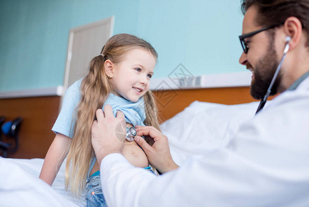 儿童医生男医生在医院用听诊器检查小女孩时背景