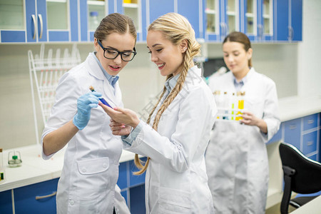 年轻女科学家在实验室测试管中检查化学样本的图片