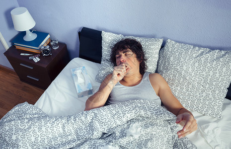 咳嗽躺在床上的年轻病人的肖像疾图片