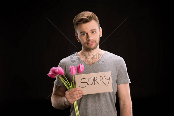 拿着郁金香花束和在黑色上隔绝的道歉标志时看着相图片