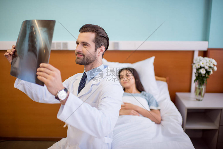 坐在女病人身边的床上和持有X光图像高清图片下载-正版图片502868625-摄图网