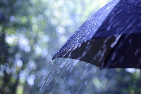 雨滴从一把黑伞上落下背景图片