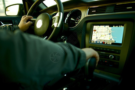 汽车导航使用导航和多媒体系统驾驶汽车与男司机的汽车内饰图片