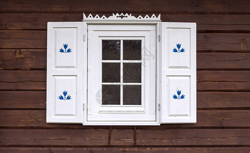 带有白色装饰窗户的旧传统木屋的正面图片