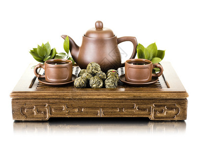 粘土茶壶和杯子在木三脚架上的静物白图片