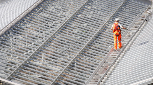 男工人身穿橙色西装在火车站钢铁屋顶背景图片
